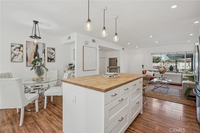 kitchen with butcher block counters, open floor plan, white cabinetry, wood finished floors, and recessed lighting