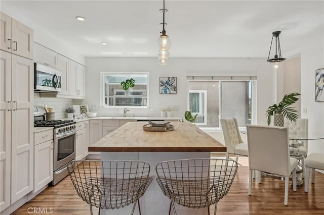 kitchen featuring appliances with stainless steel finishes, butcher block counters, plenty of natural light, light wood finished floors, and recessed lighting