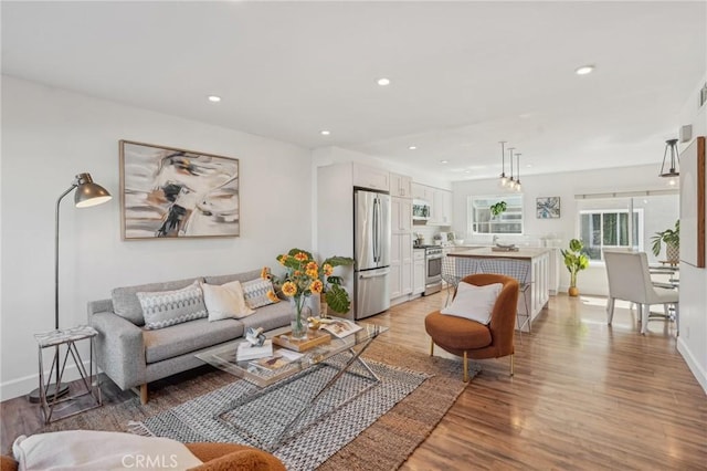 living room with light wood-style floors, recessed lighting, and baseboards