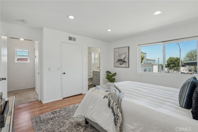 bedroom featuring wood finished floors, recessed lighting, and ensuite bathroom