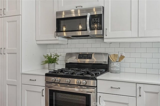 kitchen with stainless steel appliances, white cabinetry, backsplash, and light countertops