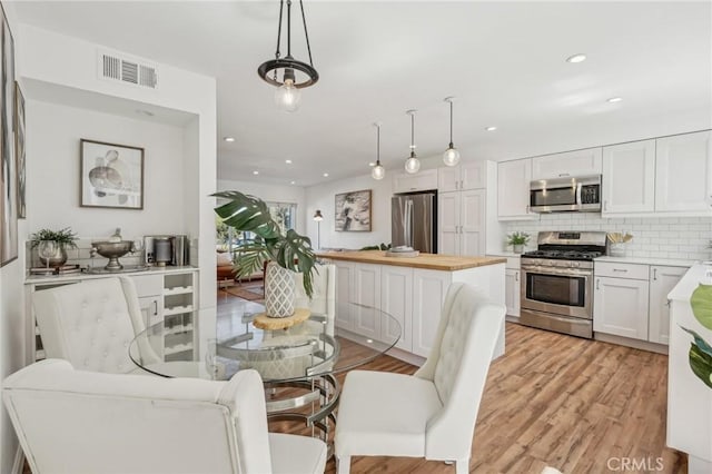 dining space with light wood finished floors and recessed lighting