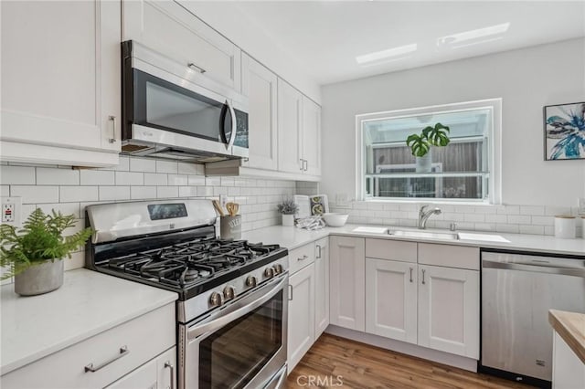 kitchen with stainless steel appliances, backsplash, white cabinets, and light countertops