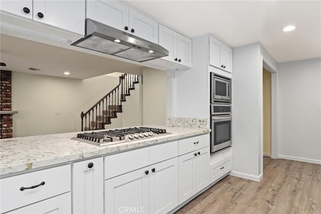 88 Auburn Ave, Sierra Madre, CA 91024 - kitchen featuring appliances with stainless steel finishes, under cabinet range hood, light wood finished floors, white cabinetry, and light stone counters