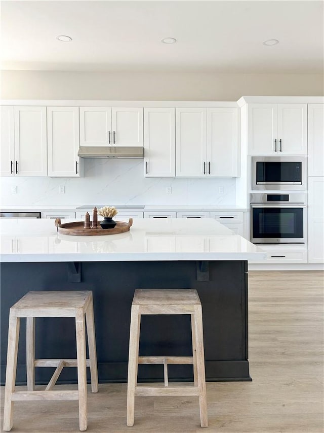 12460 San Marcos Rd, Atascadero, CA 93422 - kitchen featuring oven, built in microwave, white cabinets, a breakfast bar, and light countertops
