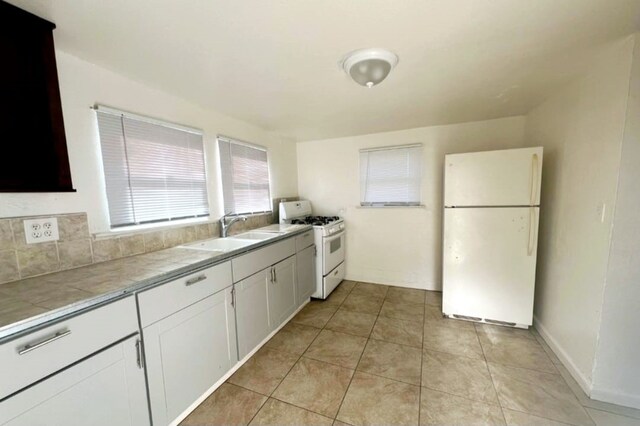 1324 Murdock St, Bakersfield, CA 93307 - kitchen featuring white appliances, tile counters, white cabinets, a sink, and light tile patterned flooring