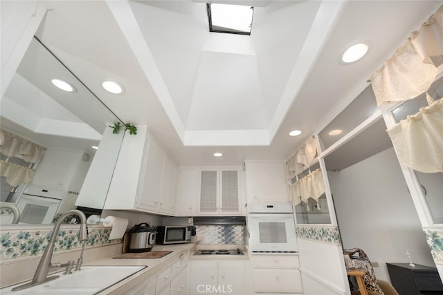 kitchen with oven, a sink, black electric stovetop, white cabinetry, and recessed lighting