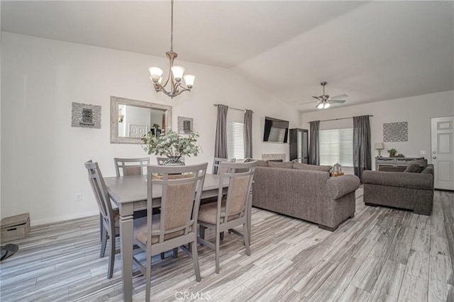 dining area featuring light wood-type flooring, lofted ceiling, a chandelier, ceiling fan, and baseboards