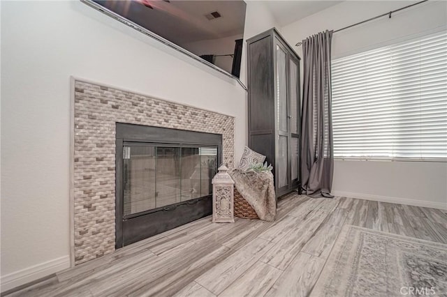 unfurnished living room with light wood finished floors, a fireplace, and baseboards