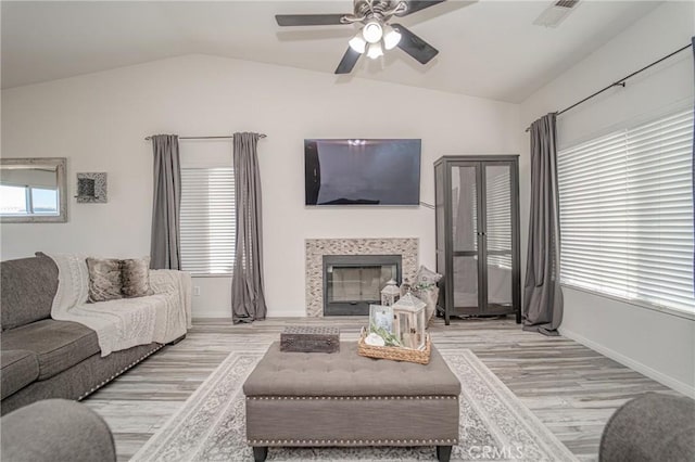 living room featuring wood finished floors, lofted ceiling, ceiling fan, baseboards, and a fireplace