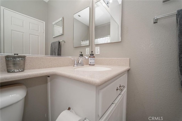 half bathroom featuring vanity and toilet