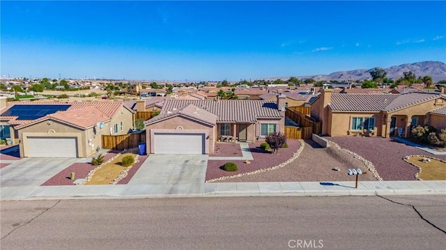 ranch-style house featuring a residential view, concrete driveway, an attached garage, stucco siding, and fence