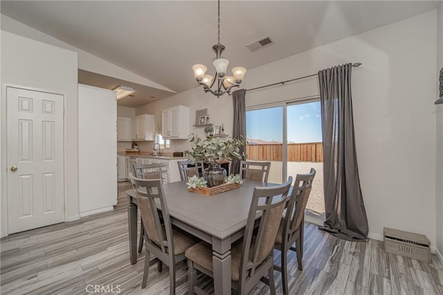 dining room with a chandelier, lofted ceiling, light wood-style floors, and baseboards