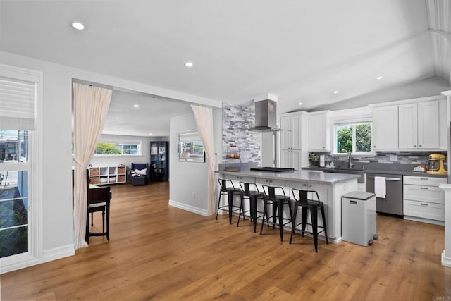 kitchen with dishwasher, ventilation hood, a kitchen bar, white cabinets, and backsplash