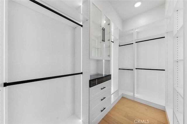 walk in closet with light wood-style floors