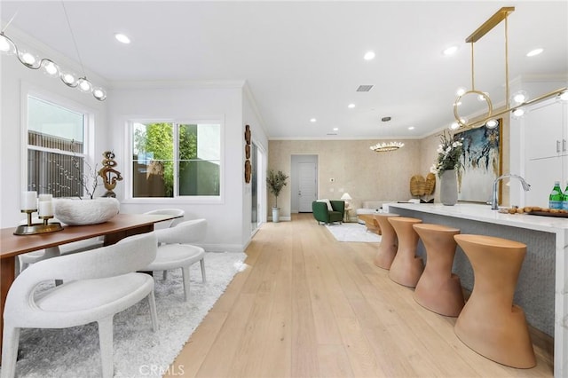dining room with light wood-style floors, ornamental molding, baseboards, and recessed lighting