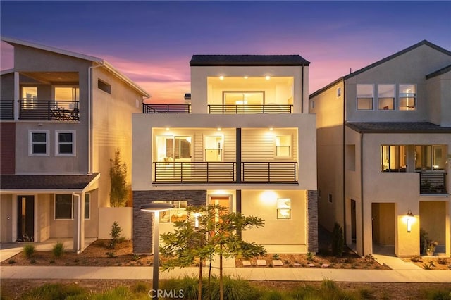 view of front of property with a balcony, stucco siding, and stone siding