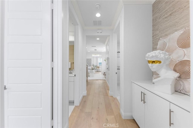 hall with light wood-type flooring, crown molding, baseboards, and recessed lighting