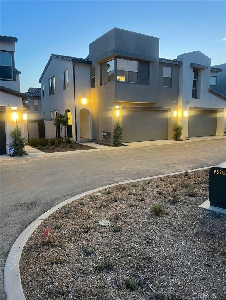view of front of home with a garage, stucco siding, and curved driveway