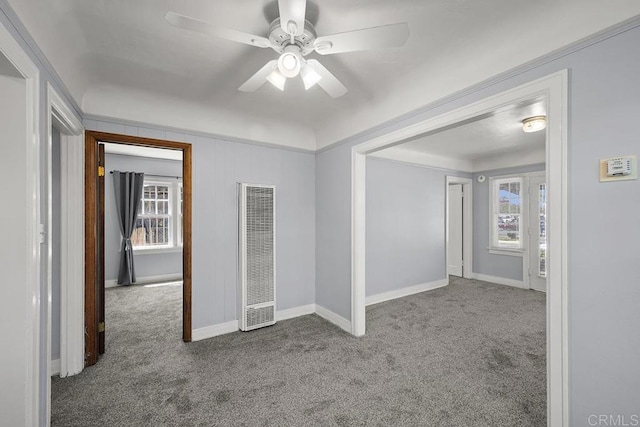 carpeted spare room featuring a heating unit, ceiling fan, and baseboards