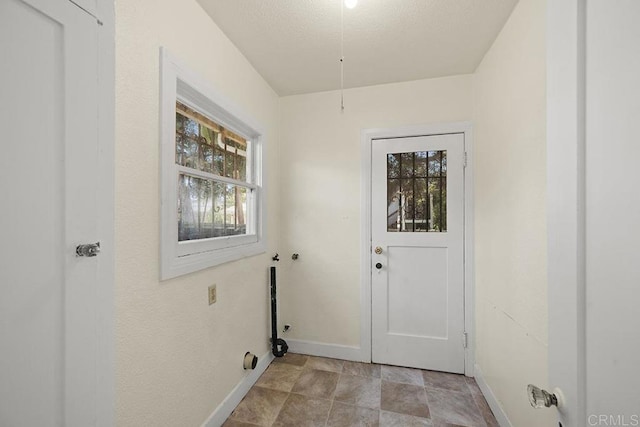 doorway to outside with baseboards, a textured ceiling, and stone finish flooring