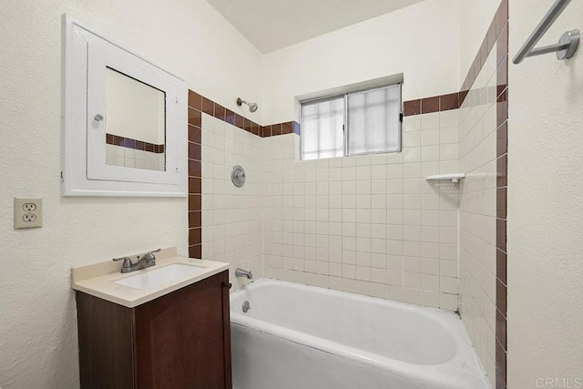 bathroom featuring washtub / shower combination, vanity, and a textured wall