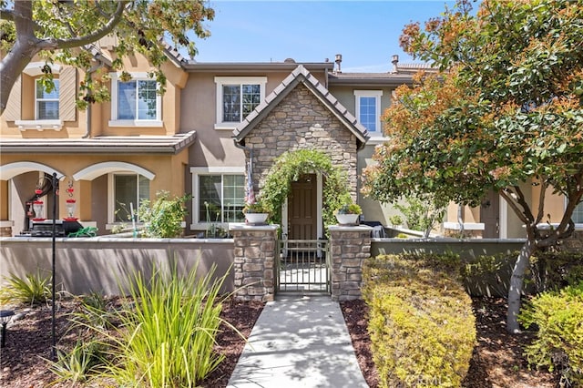 8029 Spencer St, Chino, CA 91708 - view of front of home featuring stucco siding, a fenced front yard, a gate, and stone siding