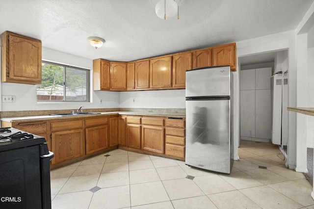 8590 N Ventura Ave, Ventura, CA 93001 - kitchen with freestanding refrigerator, black gas range oven, brown cabinets, and a textured ceiling