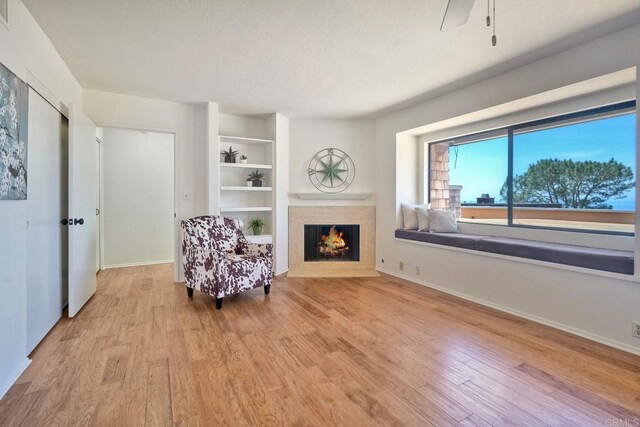 13063 Caminito Del Rocio, Del Mar, CA 92014 - sitting room with a warm lit fireplace, light wood-style flooring, built in features, and ceiling fan