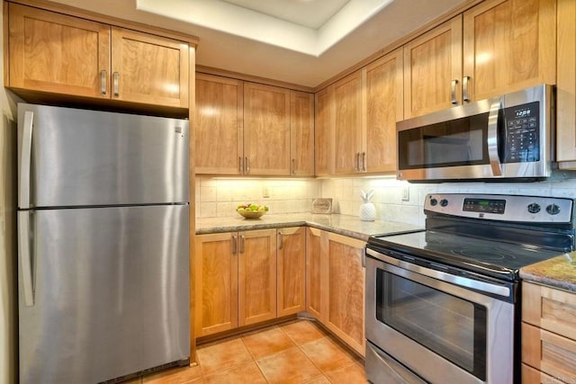 13063 Caminito Del Rocio, Del Mar, CA 92014 - kitchen featuring appliances with stainless steel finishes, light stone countertops, decorative backsplash, light tile patterned flooring, and brown cabinetry