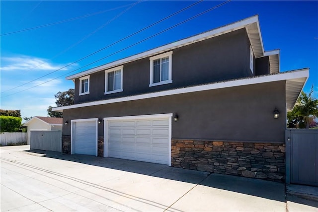 228 Del Mar Ave, Costa Mesa, CA 92627 - view of side of property with stucco siding, stone siding, an attached garage, and concrete driveway