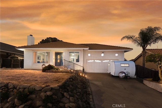16503 Mountain St, Lake Elsinore, CA 92530 - view of front of house with a tiled roof, an attached garage, driveway, a chimney, and fence