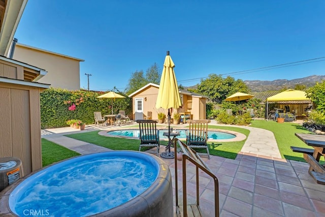 view of pool with a hot tub, a patio area, an outdoor structure, and a mountain view