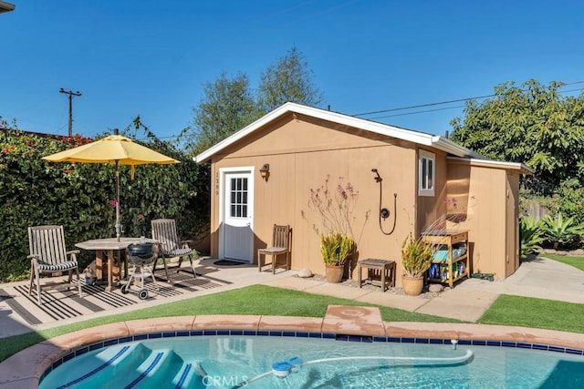 back of property featuring an outdoor structure, an outdoor pool, and a patio area