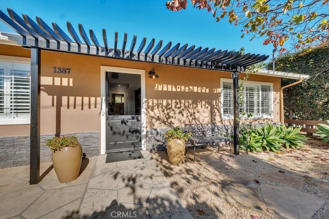 entrance to property featuring a pergola and stucco siding