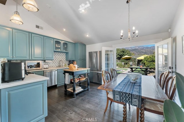 kitchen featuring stainless steel appliances, vaulted ceiling, light countertops, a chandelier, and decorative backsplash