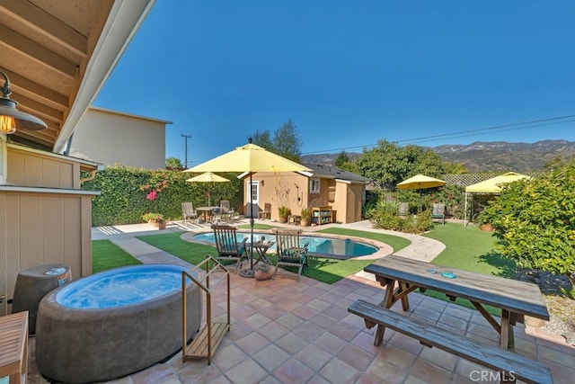 view of pool featuring a patio area, a mountain view, fence, and an outbuilding