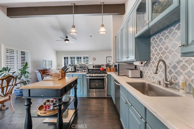 kitchen with stainless steel range with gas cooktop, a sink, light countertops, backsplash, and a ceiling fan