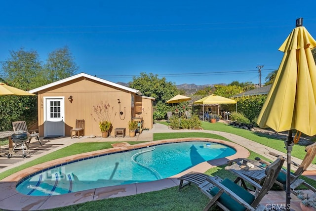 view of pool with a patio area, an outdoor structure, a lawn, and a mountain view