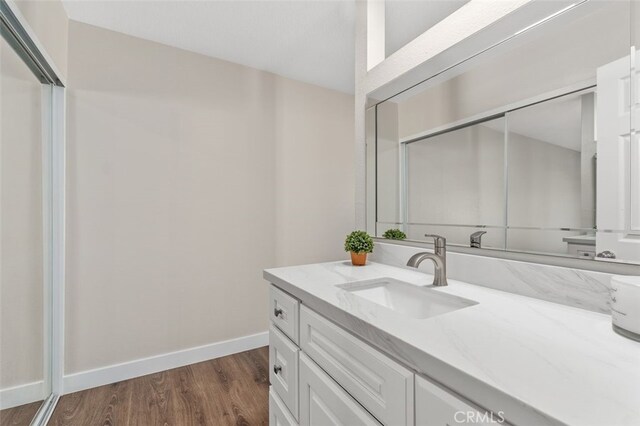 bathroom featuring baseboards, wood finished floors, and vanity