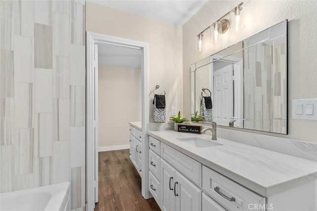 full bath with wood finished floors, vanity, and a bath