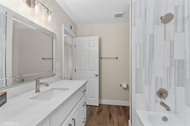 bathroom featuring bathing tub / shower combination, wood finished floors, vanity, and baseboards