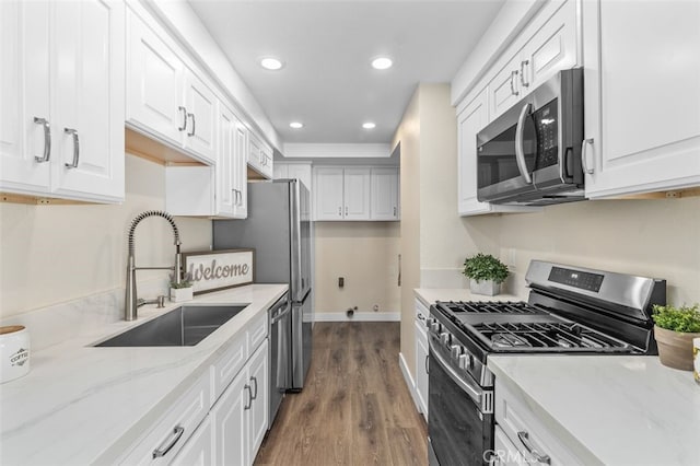 kitchen featuring appliances with stainless steel finishes, a sink, recessed lighting, dark wood-style flooring, and light stone countertops