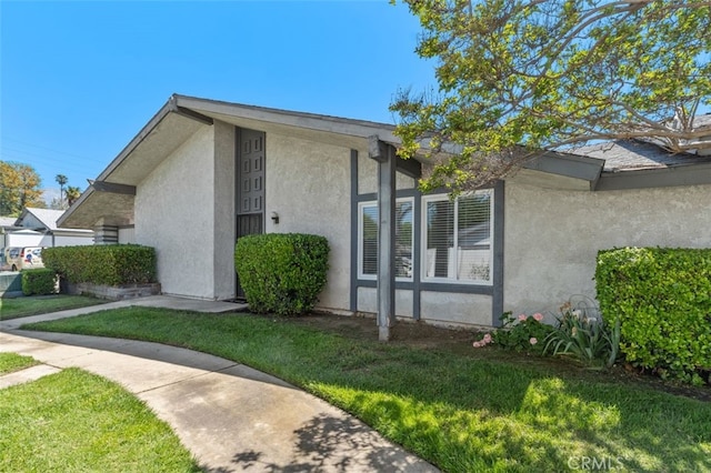 view of side of home featuring stucco siding and a lawn