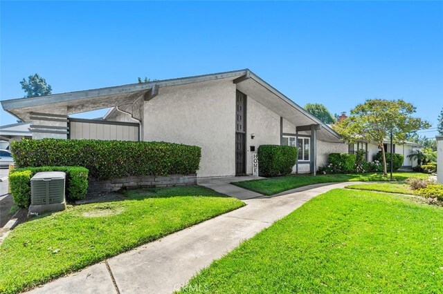 view of side of property with a yard, stucco siding, and central air condition unit