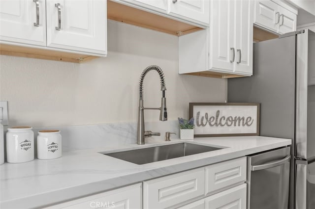 kitchen with a sink, white cabinets, appliances with stainless steel finishes, and light stone counters