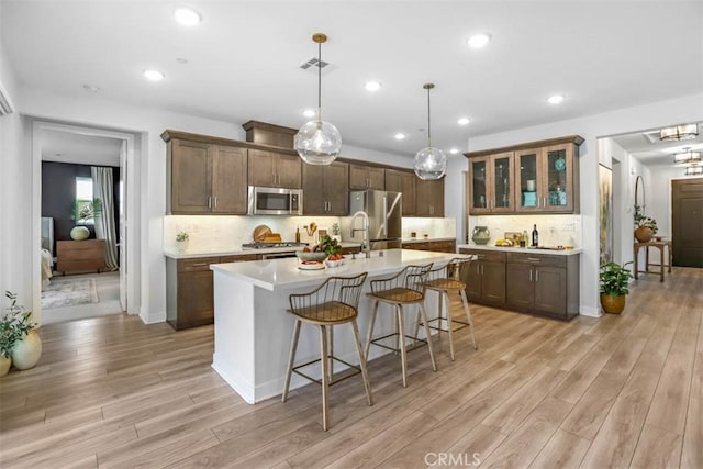 1772 Lundy Ln, Beaumont, CA 92223 - kitchen with appliances with stainless steel finishes, light wood-style flooring, a kitchen breakfast bar, light countertops, and an island with sink