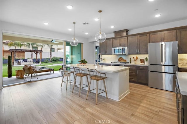 1772 Lundy Ln, Beaumont, CA 92223 - kitchen featuring stainless steel appliances, light countertops, a kitchen breakfast bar, light wood finished floors, and recessed lighting
