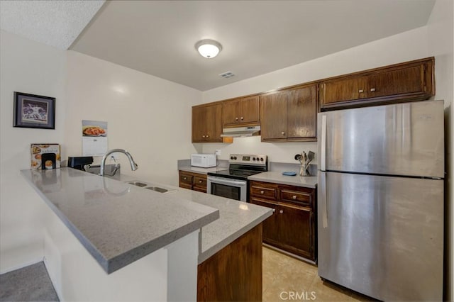 kitchen featuring appliances with stainless steel finishes, a sink, under cabinet range hood, a peninsula, and light tile patterned flooring
