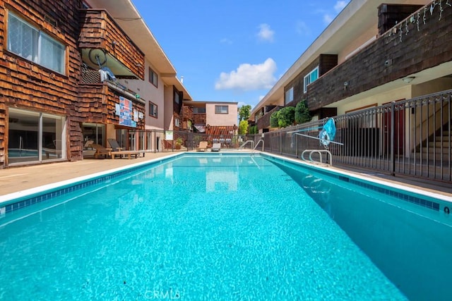community pool featuring fence and a residential view